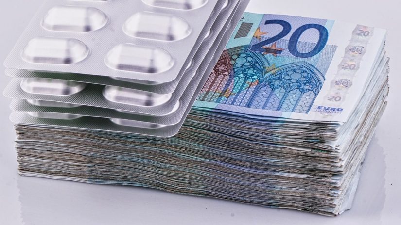 a stack of 20 euro bills next to a pack of 20 pills